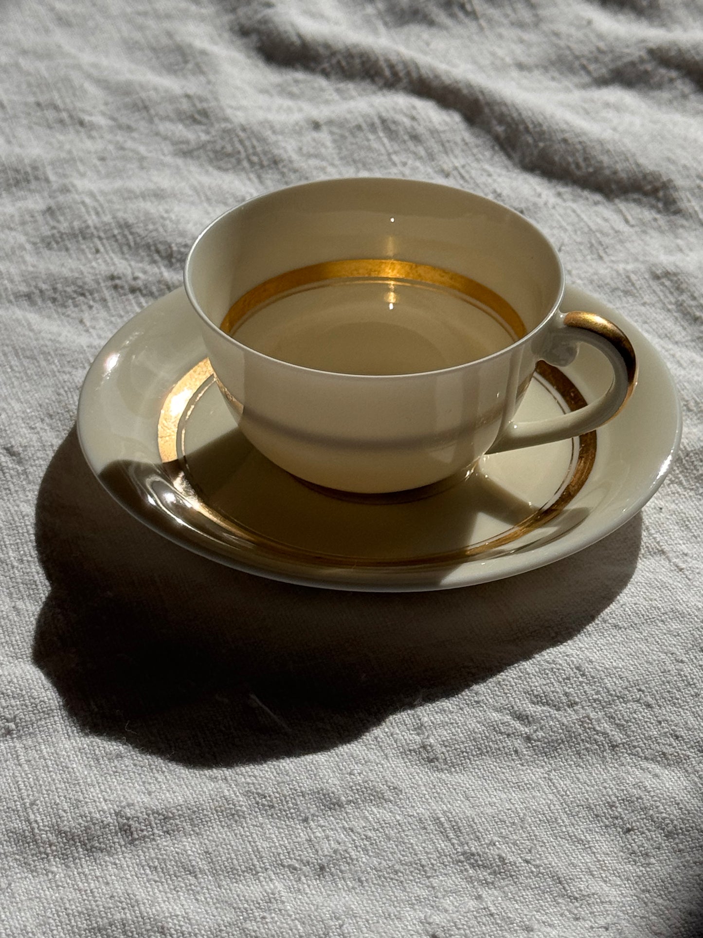 Tasse à café en fine porcelaine de Limoges blanche et filets d'or.