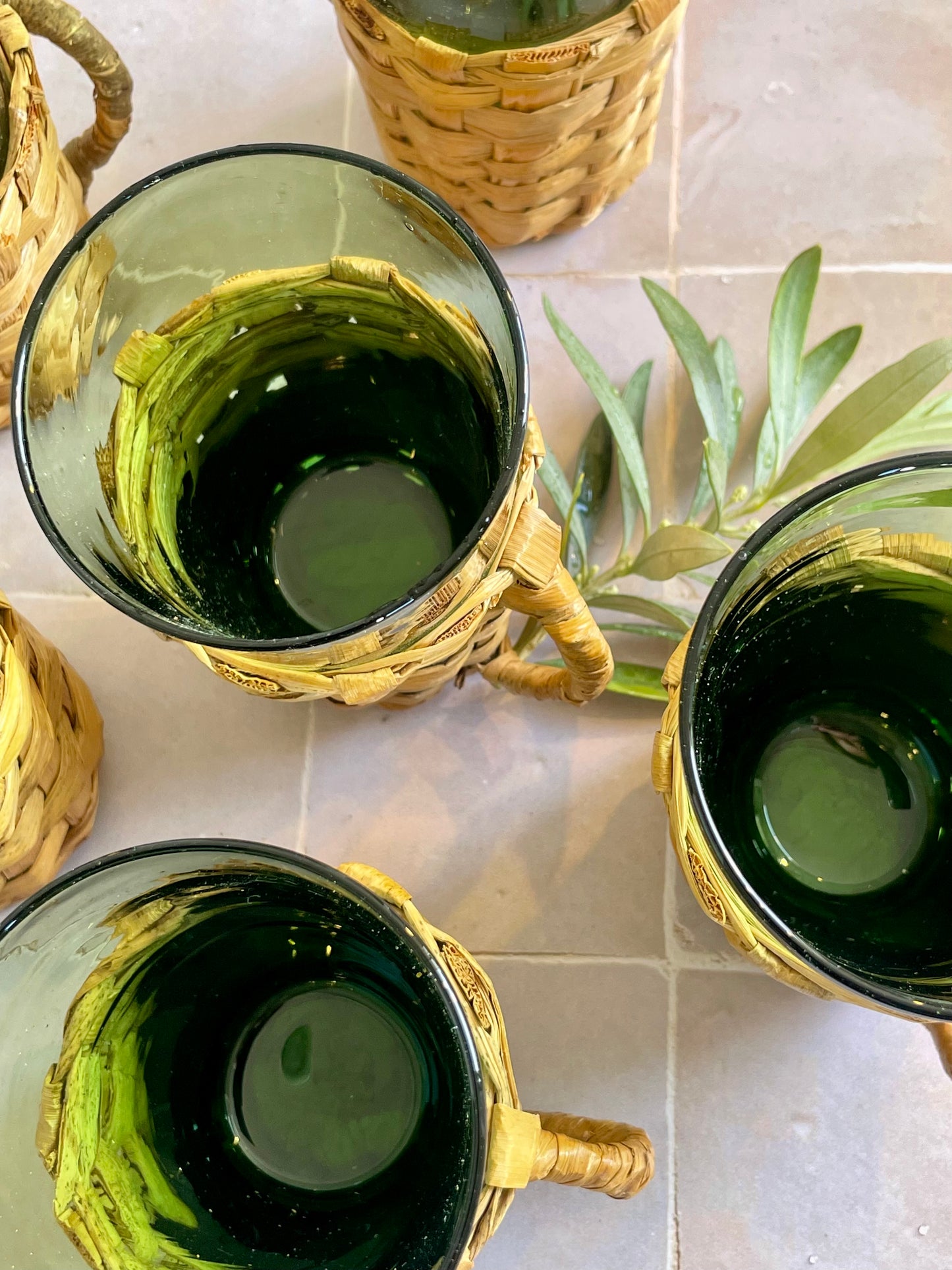 6 verres années 70 présentés dans leurs porte-verres en osier tressé.